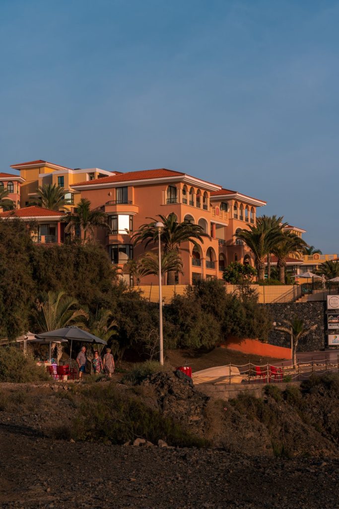 Edificio residencial de estilo canario con palmeras al atardecer en Costa Adeje