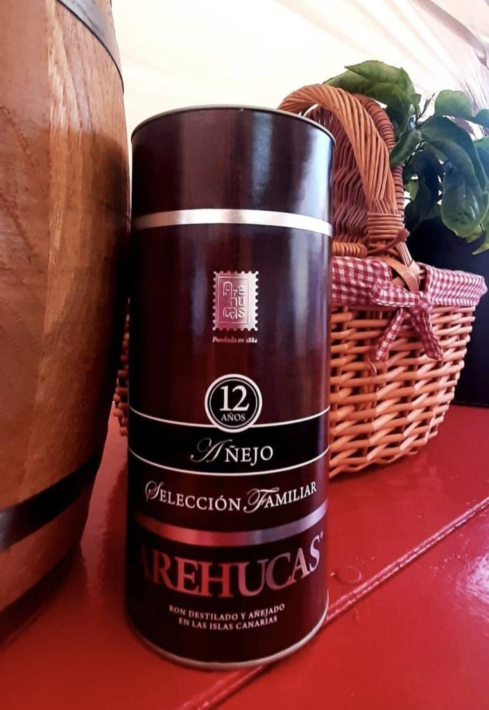 Ron añejo canario expuesto junto a una barrica y una cesta de mimbre
